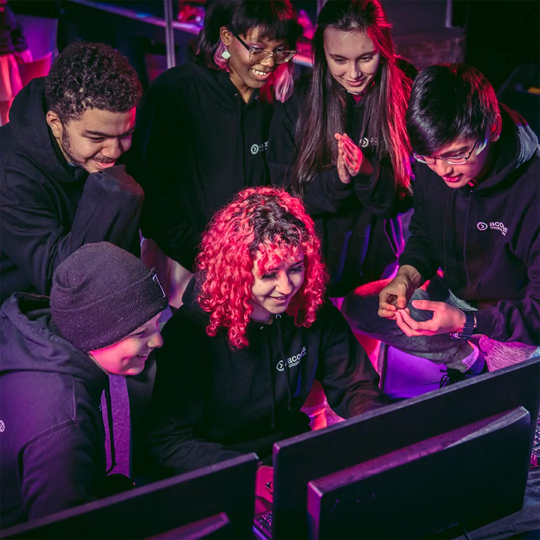 A group of 6 people sat around a computer