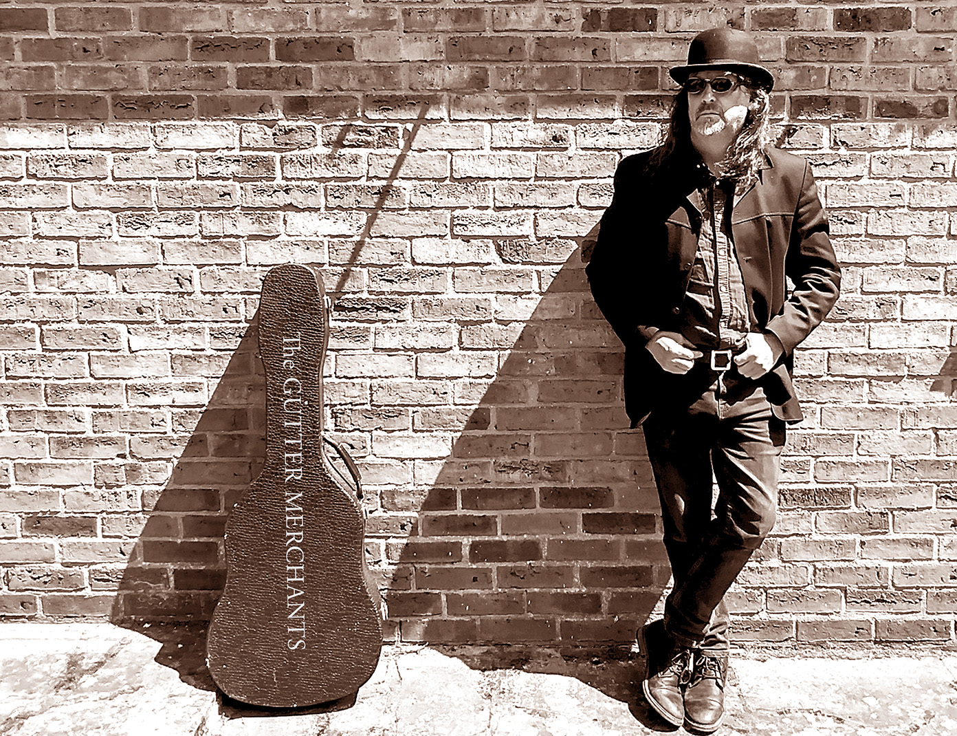 Martin Smith, Careers Leader at ACC, leaning on wall with guitar case next to him.