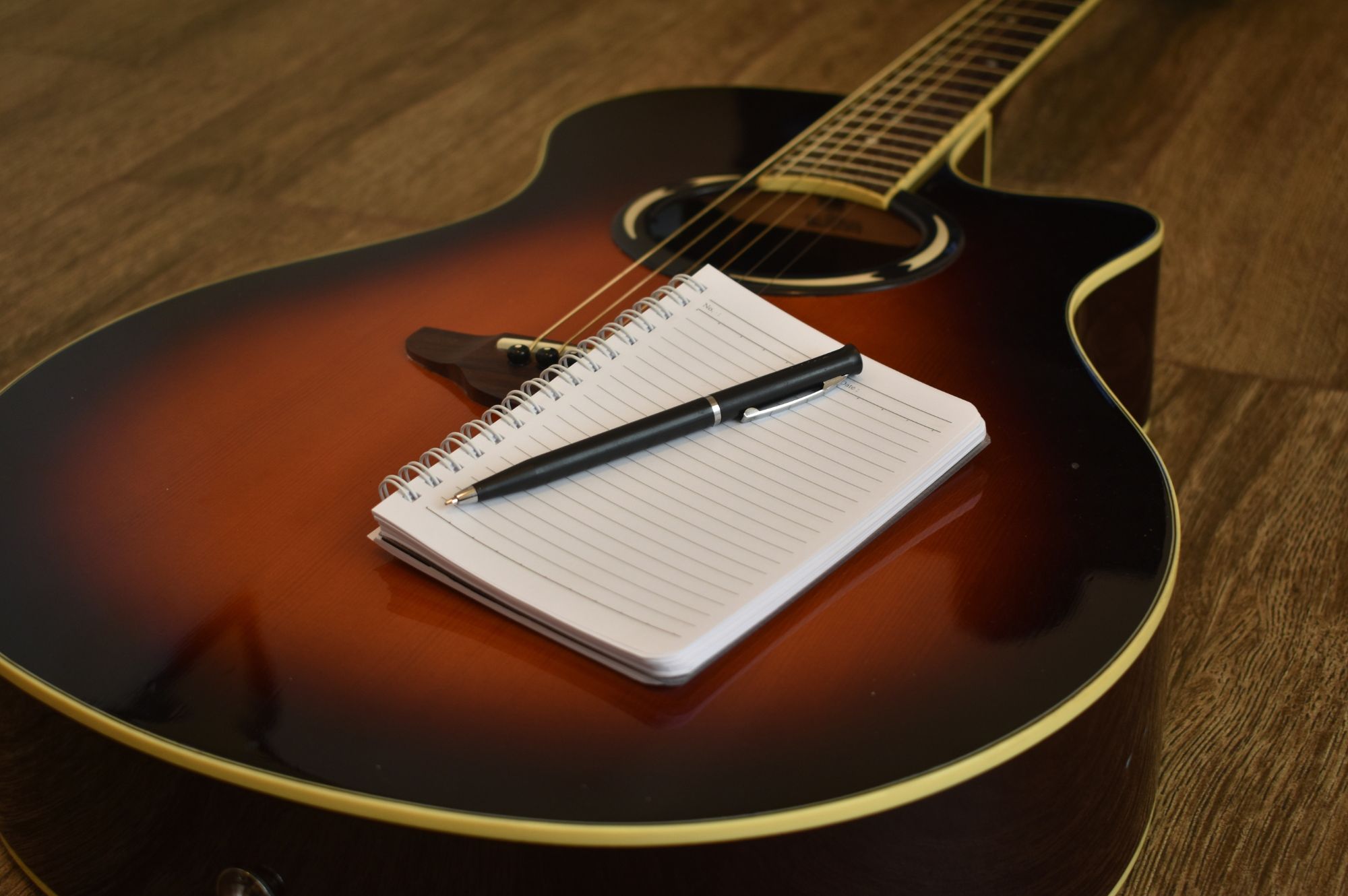 Pen and paper on top of guitar for songwriter